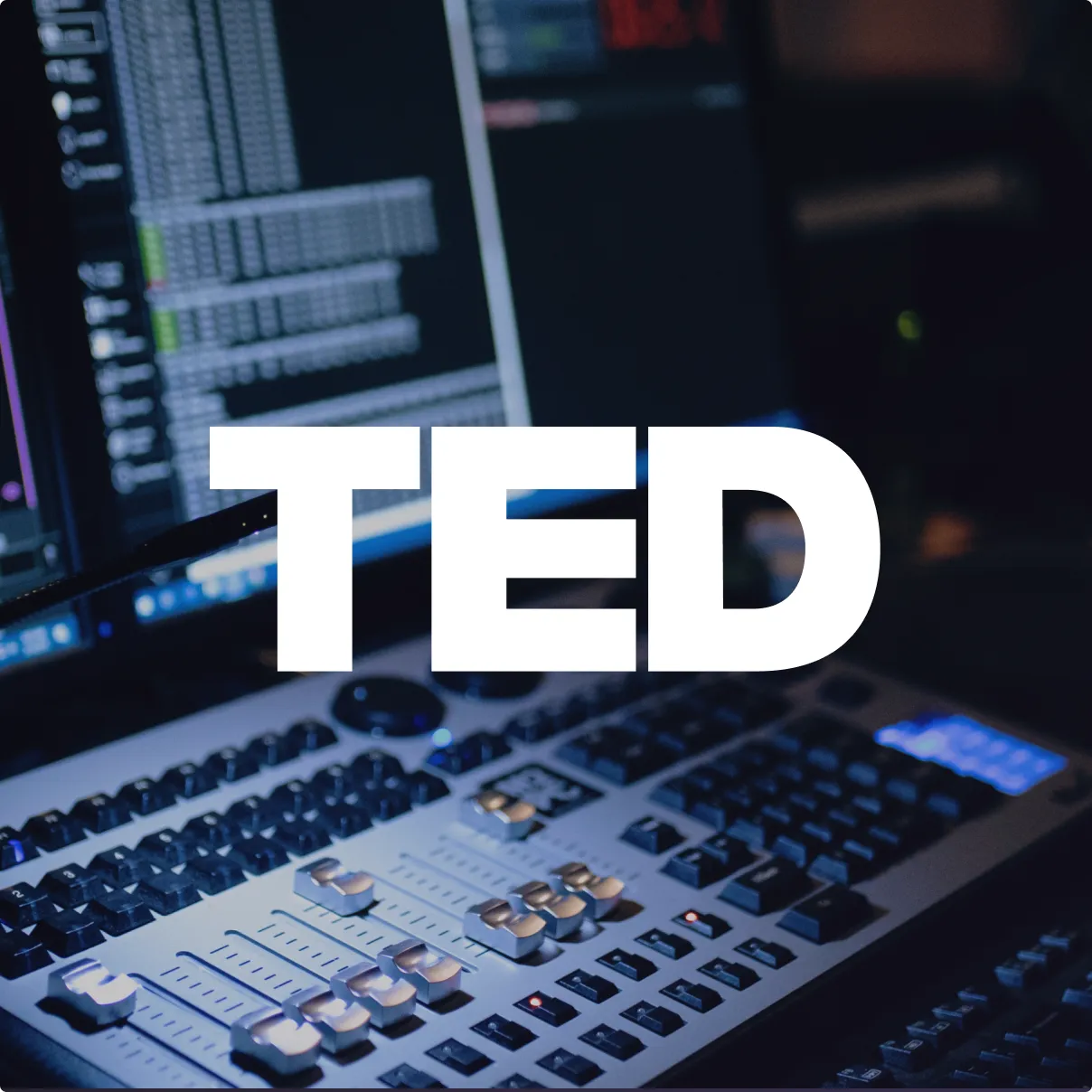 Audio mixing console with faders and controls lit in blue light under the large white text TED.